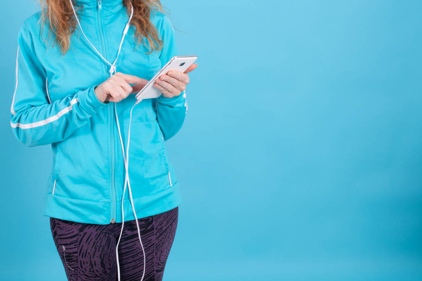 mains de femme avec téléphone portable et vêtements de sport sur fond bleu
 - Photo, image