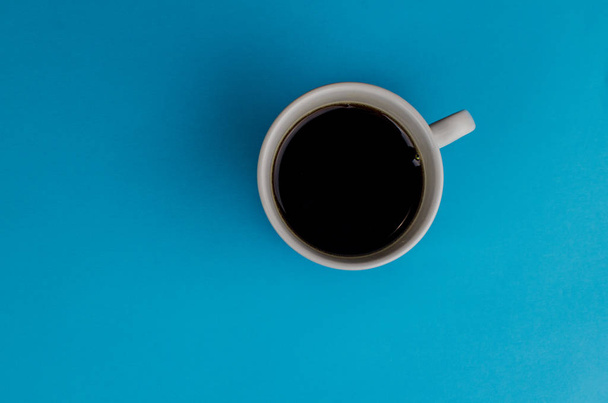 eine Tasse frischen Kaffee auf blauem Hintergrund mit Textfläche. flach lag. Ansicht von oben. Minimalismus - Foto, Bild