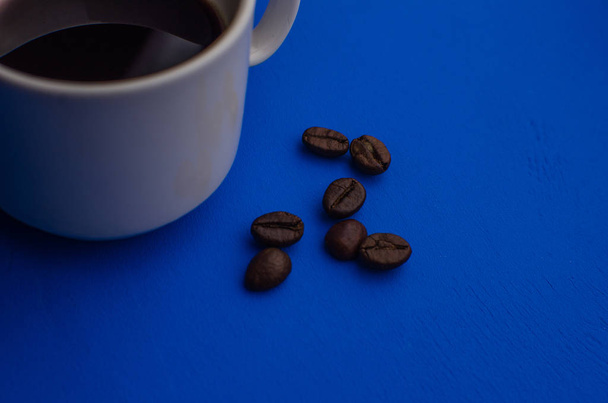Tazza di caffè espresso con chicchi di caffè su sfondo blu. Posa piatta, design creativo
. - Foto, immagini