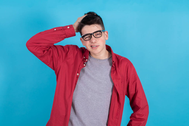 thoughtful young man with glasses and casual style isolated on blue background - Valokuva, kuva