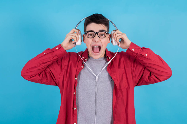 young teenage man with headphones isolated on blue background - Photo, Image