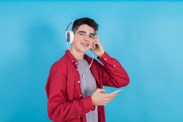 modny młody człowiek z telefonem i słuchawkami izolowane na tle koloru - Zdjęcie, obraz