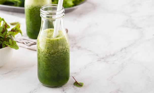 Blended green smoothie with ingredients on the white table. - Foto, imagen