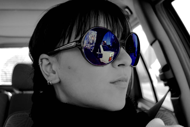 νεαρή γυναίκα με γυαλιά ηλίου κάθεται στο αυτοκίνητο - Φωτογραφία, εικόνα