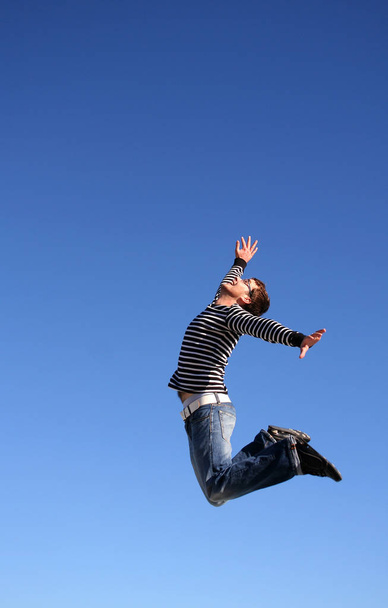 young woman jumping on the blue sky - Foto, afbeelding