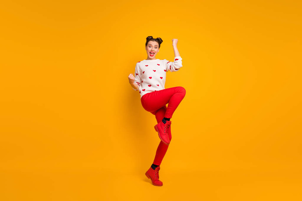 Full body photo of beautiful cupid lady raise fists one leg celebrating romantic date invitation wear hearts pattern white sweater red pants footwear isolated yellow color background - Φωτογραφία, εικόνα