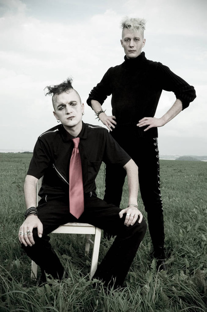 young man and woman in black suit and boots with a gun - Фото, зображення
