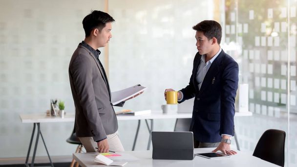 Vista de perto de dois homens de negócios discutindo sobre sua tarefa na moderna sala de reuniões
 - Foto, Imagem