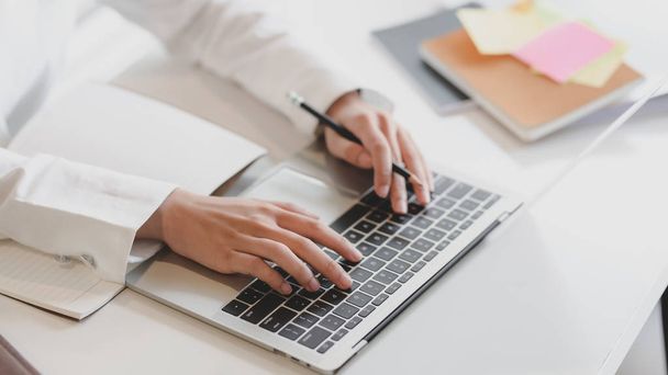 Plan recadré de femme d'affaires travaillant sur un ordinateur portable et un ordinateur portable avec des fournitures de bureau sur une table blanche
  - Photo, image