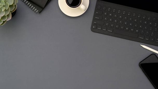Вид зверху робочого простору з копіювальним простором, цифровим планшетом, смартфоном, приладдям для офісу та чашкою кави на сірому фоні столу
 - Фото, зображення