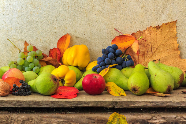 autumnal still life with fruit and leaves on a wooden base - Foto, Bild