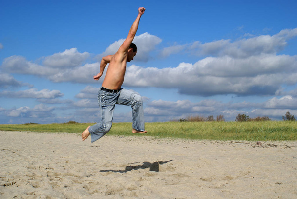 young man jumping on the beach - Fotó, kép