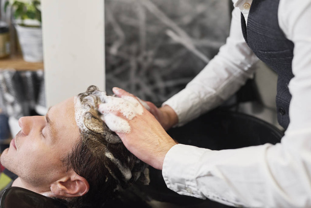 Nahaufnahme von Friseur wäscht Mann Haare  - Foto, Bild