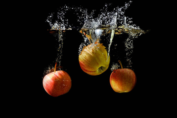 Siyah arkaplanda suya düşen üç elma.. - Fotoğraf, Görsel