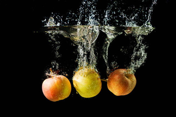 Siyah arkaplanda suya düşen üç elma.. - Fotoğraf, Görsel