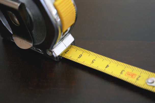 yellow tape measure on wooden background - 写真・画像