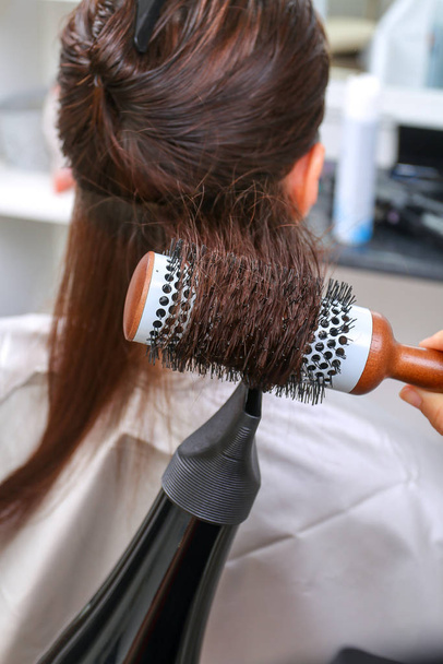 Girl in beauty salon while an hair stylist dry her hair - Photo, Image