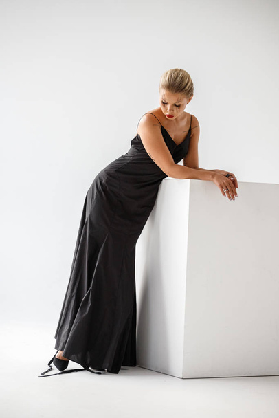 Lovely blonde girl in black dress posing on white background - Foto, afbeelding