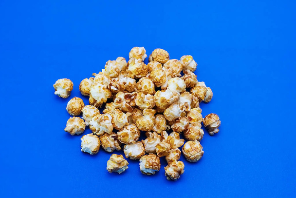 Karamell-Popcorn auf blauem Hintergrund. Filmkonzept. Nahrung zum Filmgucken. Blick von oben. 2020 blaue Hintergrundfarbe - Foto, Bild