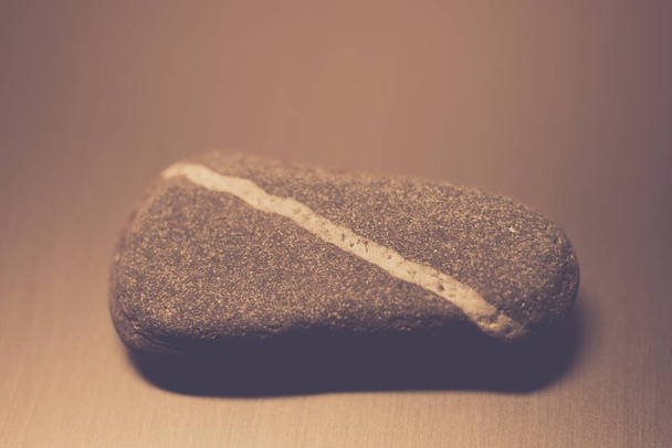 Камень с естественной диагональной белой линией на столе
. - Фото, изображение