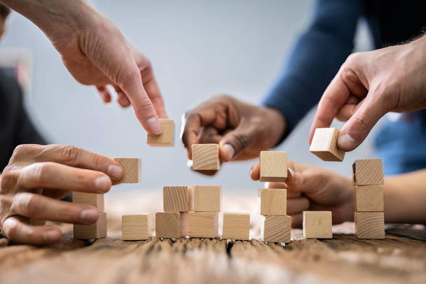 Close-up Of Businesspeople's Hand Stacking Wooden Blocks - Foto, imagen