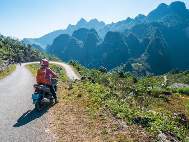 One person riding bike on Ha Giang motorbike loop, famous travel destination bikers easy riders. Ha Giang karst geopark mountain landscape in North Vietnam. Winding road in stunning scenery.  - Photo, image