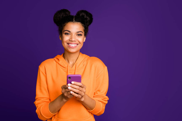 Photo of cheerful positive toothy beaming cute nice pretty woman with telephone held hands standing near empty space looking at you isolated vivid purple color background - Valokuva, kuva