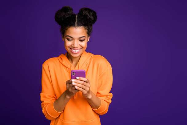 Photo of cheerful positive cute pretty nice woman smiling toothily looking into telephone for new information isolated vivid color purple background - Fotografie, Obrázek