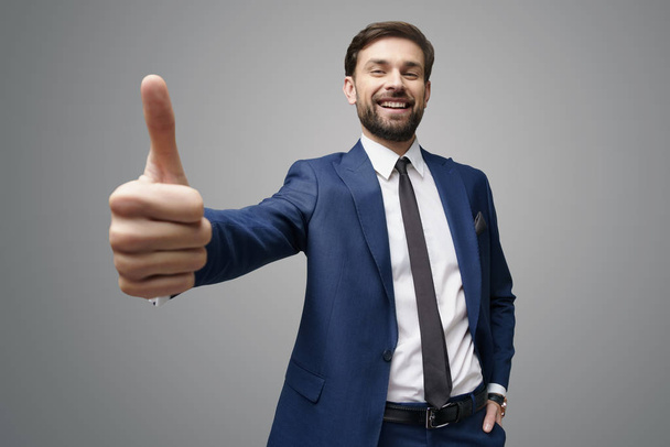 wide angle selfie shot of young business man going thumb up on grey background - Fotografie, Obrázek