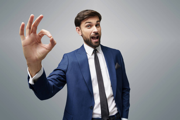 wide angle selfie shot of young business man showing ok sign on grey background - Фото, зображення