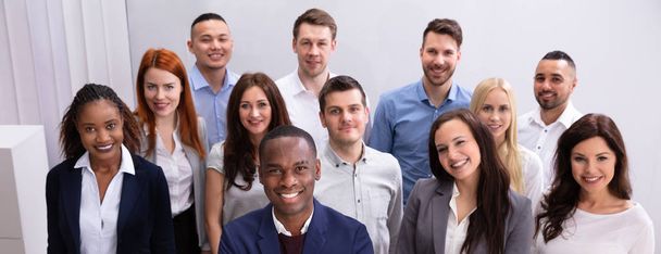 Group Of Young Successful Multi-ethnic Businesspeople Standing In Office Looking At Camera - Foto, immagini