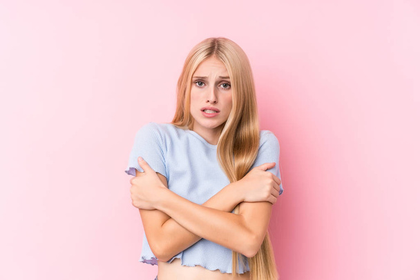 Young blonde woman on pink background going cold due to low temperature or a sickness. - Foto, imagen