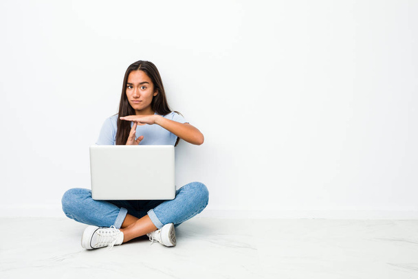 Young mixed race indian woman sitting working on laptop showing a timeout gesture. - 写真・画像