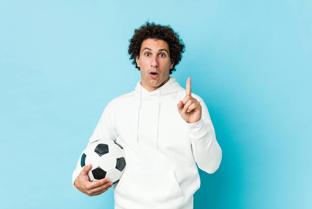 Sportowy mężczyzna trzymający piłkę nożną mając jakiś świetny pomysł, pojęcie kreatywności. - Zdjęcie, obraz