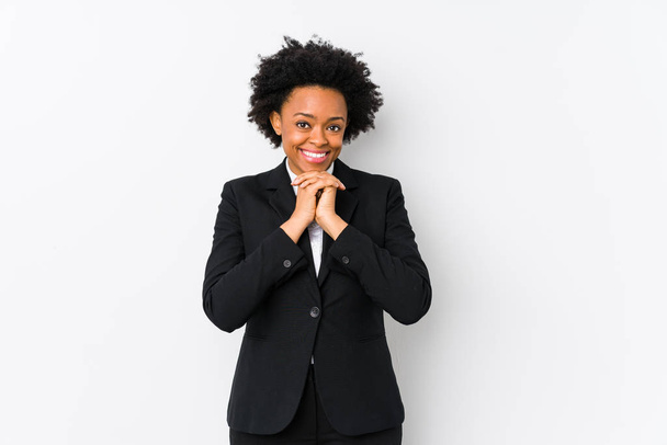 Μεσήλικας αφροαμερικανίδα επιχειρηματίας σε λευκό φόντο απομονωμένη κρατά τα χέρια κάτω από το πηγούνι, ψάχνει ευτυχώς στην άκρη. - Φωτογραφία, εικόνα