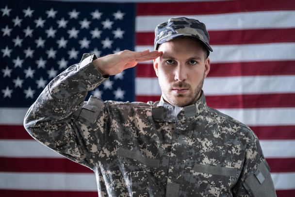 Portret van Army Soldier Saluting Voor American Flag - Foto, afbeelding