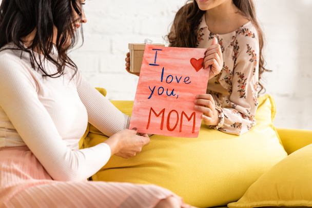 cropped view of child presenting mothers day card with i love you mom inscription to mother - Fotografie, Obrázek