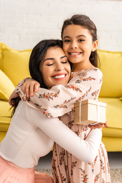 happy woman holding mothers day present while hugging adorable daughter - Foto, Bild