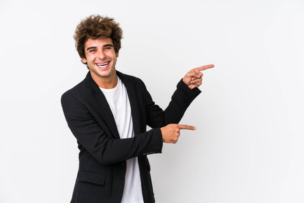 junger kaukasischer Geschäftsmann vor weißem Hintergrund vereinzelt aufgeregt mit Zeigefingern wegzeigend. - Foto, Bild