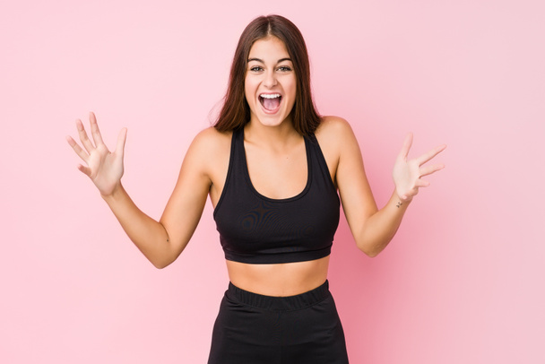 Jovem caucasiano fitness mulher fazendo esporte isolado recebendo uma agradável surpresa, animado e levantando as mãos
. - Foto, Imagem