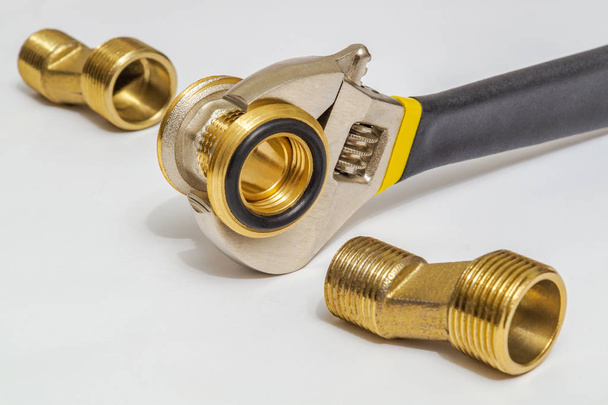 Conjunto de accesorios de latón y herramienta se utiliza a menudo para instalaciones de agua y gas sobre fondo gris
 - Foto, imagen