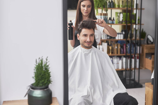 Female hairdresser  is creating trendy hairstyle her male customer - Photo, Image