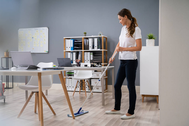 Full Length Of Female Janitor Mopping Floor In Office - Foto, immagini