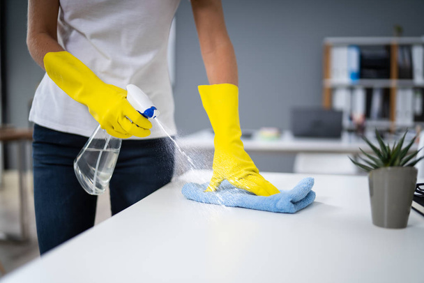 Young Worker Cleaning Desk With Rag In Office - Foto, Imagen