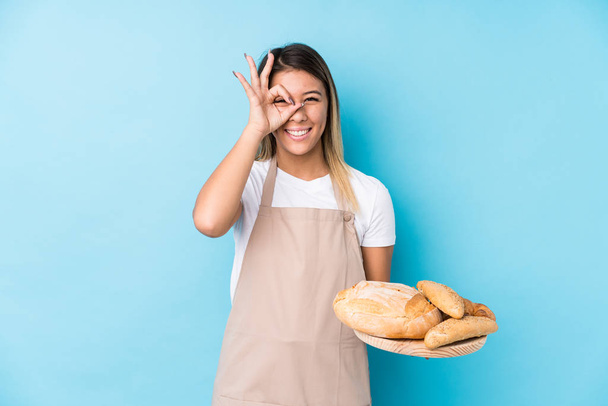 Young caucasian baker woman isolated excited keeping ok gesture on eye. - Foto, afbeelding