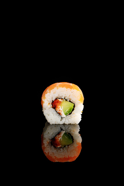 νόστιμο Φιλαδέλφεια σούσι με αβοκάντο, κρεμώδες τυρί, σολομό και χαβιάρι masago απομονώνονται σε μαύρο χρώμα με αντανάκλαση - Φωτογραφία, εικόνα