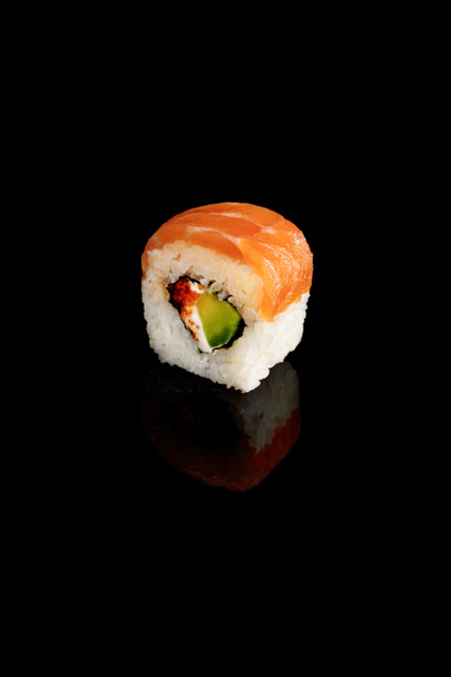 fresh delicious Philadelphia sushi piece with avocado, creamy cheese, salmon and masago caviar isolated on black - Foto, Imagem