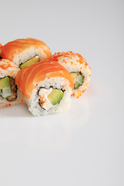 close-up uitzicht op heerlijke Philadelphia en Californië sushi met zalm en masago kaviaar op witte achtergrond - Foto, afbeelding