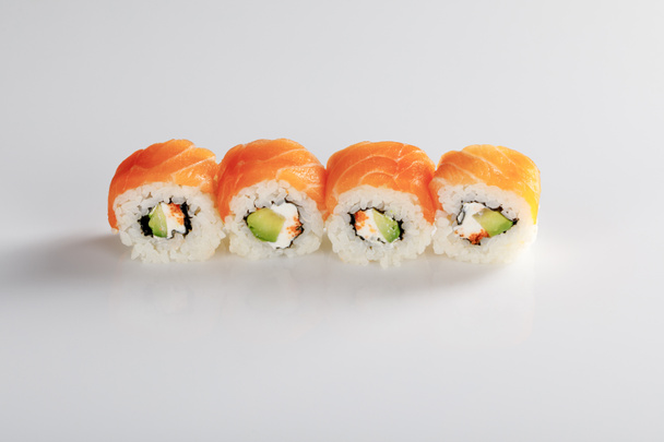 delicious Philadelphia sushi with avocado, creamy cheese, salmon and masago caviar on white background - Фото, изображение