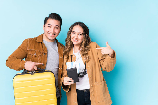 Young couple ready for a travel isolated person pointing by hand to a shirt copy space, proud and confident - Photo, Image